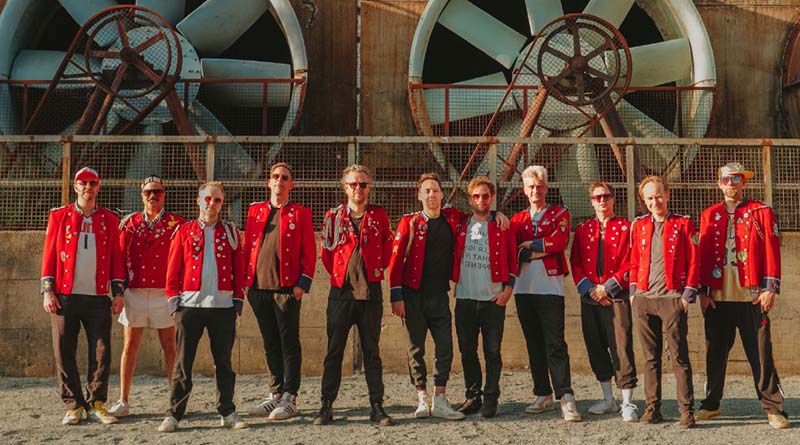 Los once integrantes de MEUTE posan con sus característicos uniformes rojos de músico de banda