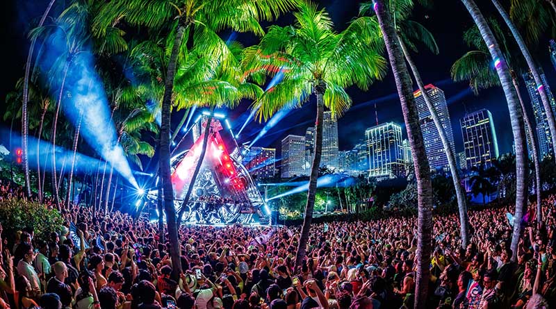 Público en The Cove, escenario de RESISTANCE en Ultra Miami, con los rascacielos de Miami iluminados al fondo durante la noche